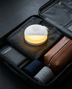Sleep machine packed inside an open suitcase with travel essentials