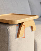 Bamboo tray clamp legs gripping a sofa armrest, detail highlighted