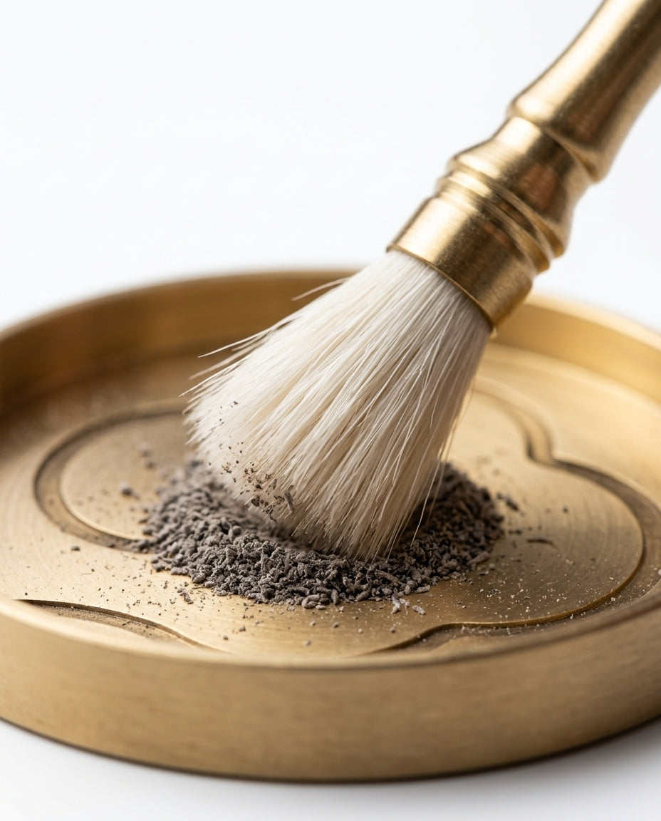 Soft-bristle brass brush sweeping incense powder on the engraved tray