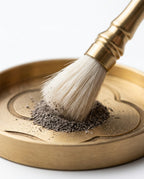 Soft-bristle brass brush sweeping incense powder on the engraved tray