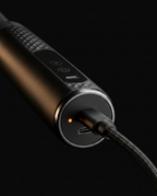 USB-C cable charging the fascia massage gun with an orange charge indicator