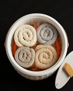 Top view of four rolled towels steaming inside the warmer bucket