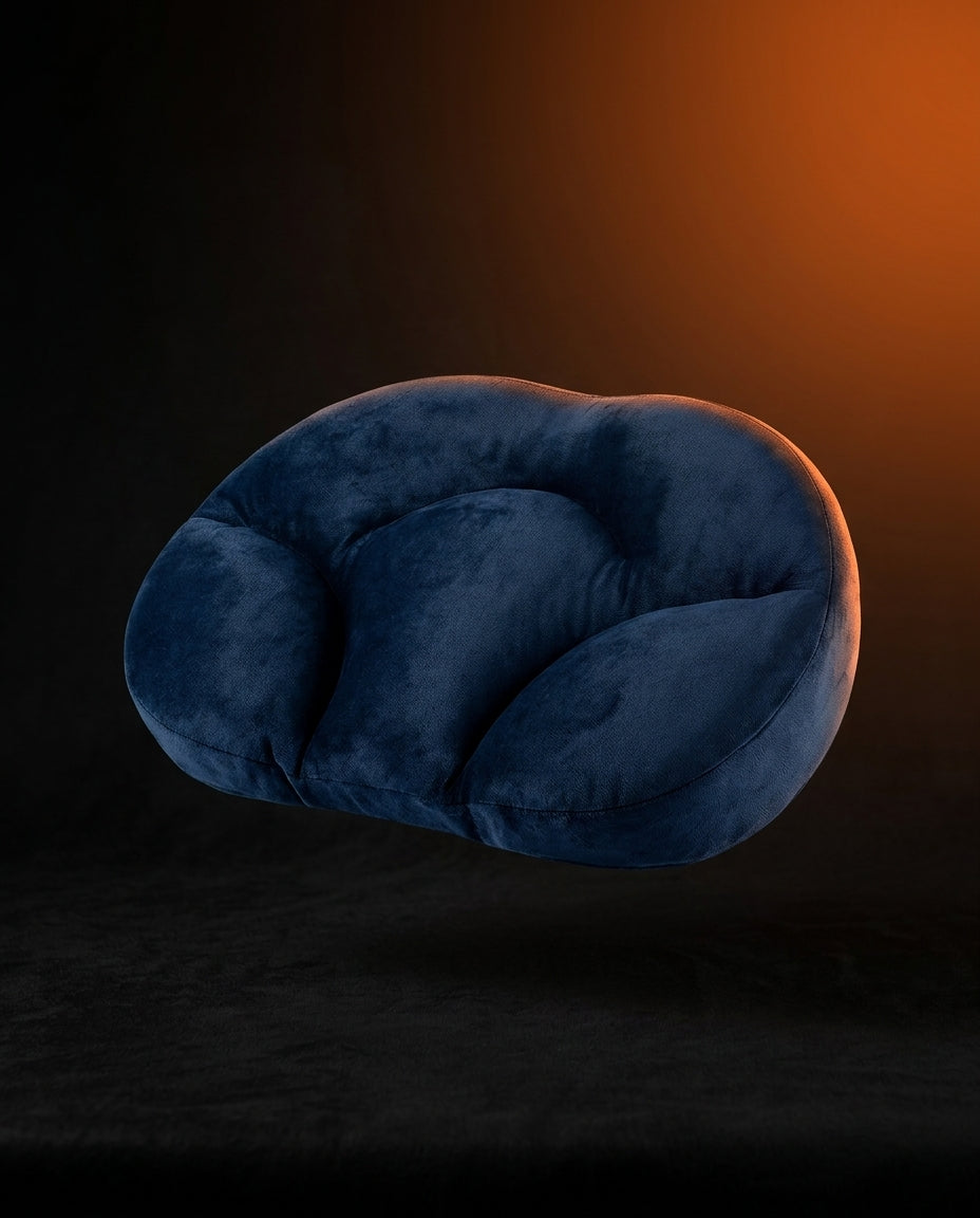 Navy blue ergonomic neck support pillow against a dark orange-lit background
