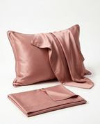 Dusty rose pink silk pillowcase on a pillow with a folded spare