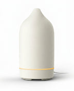 White ceramic essential oil diffuser with glowing base ring, on white