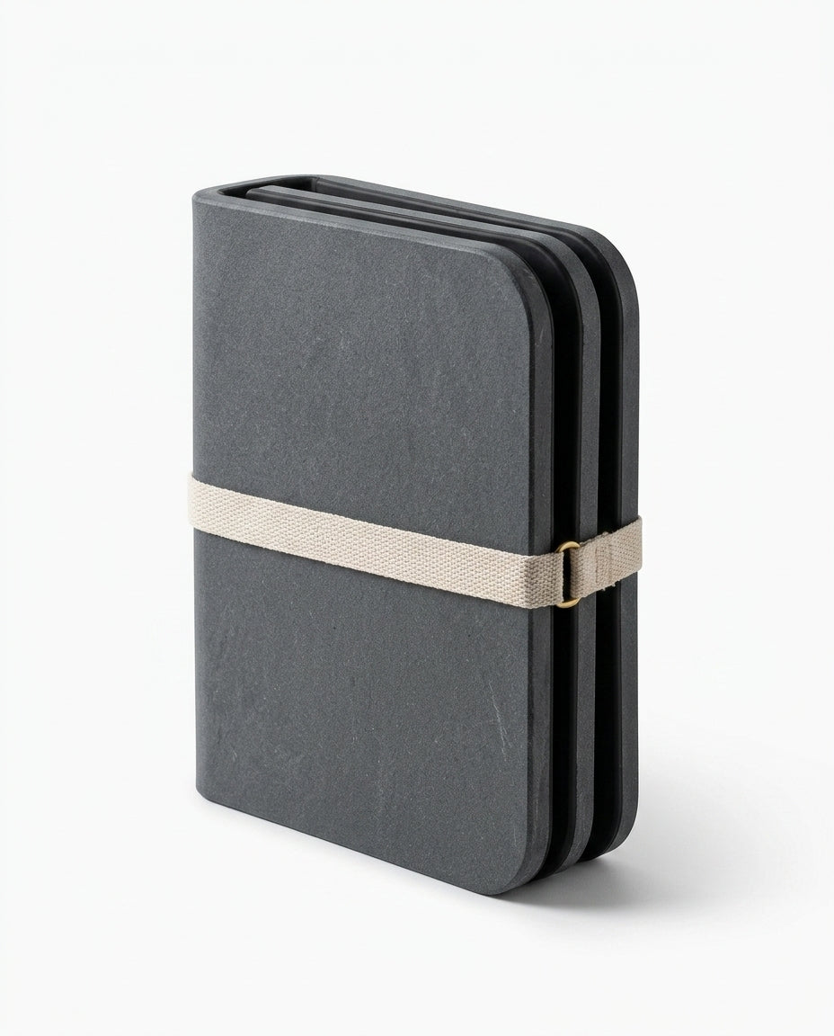 Grey stone bath mat folded compactly and held with a strap for travel