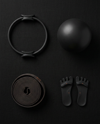 Flatlay of the pilates ring, ball, resistance band and toe separators in black