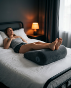 Woman on a bed resting her legs elevated on a grey inflatable wedge pillow