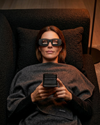Woman reclining in a chair scrolling her phone through prism reading glasses