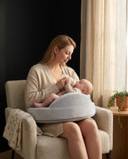 Mother bottle-feeding her baby on the feeding pillow in a nursery chair