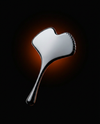 Three-quarter packshot of the silver facial sculpting tool on dark amber backdrop