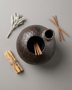 Top-down view of the ceramic burner with palo santo sticks and sage bundle