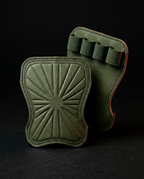 Pair of army green grip pads, one upright showing finger loops, on dark