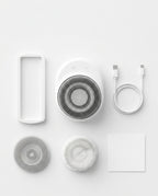 Flat-lay of the shower scrubber with wall mount, USB cable and brush heads