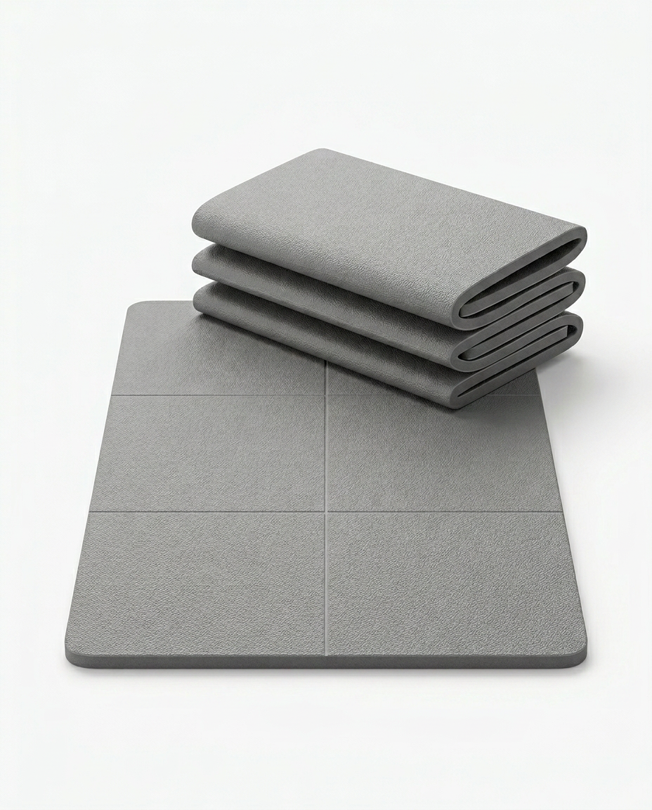 Grey foldable yoga mat shown partly folded and laid flat on white