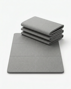 Grey foldable yoga mat shown partly folded and laid flat on white