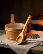 Styled sauna bucket and ladle on a rustic bench with linen towel and eucalyptus