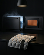 Comfort pad on a dark kitchen counter beside a freezer and microwave