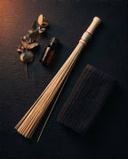 Spa flat-lay of the bamboo roller with eucalyptus, oil and a dark towel