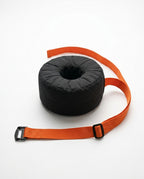 Black donut ankle cushion with the orange strap fully extended on white
