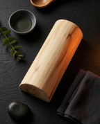 Wooden sauna neck pillow flat lay with tea, leaves and towel on slate