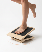Bare foot tilting the wooden ankle balance board during a single-leg exercise