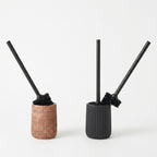 Brown and black ribbed toilet brush holders side by side on white