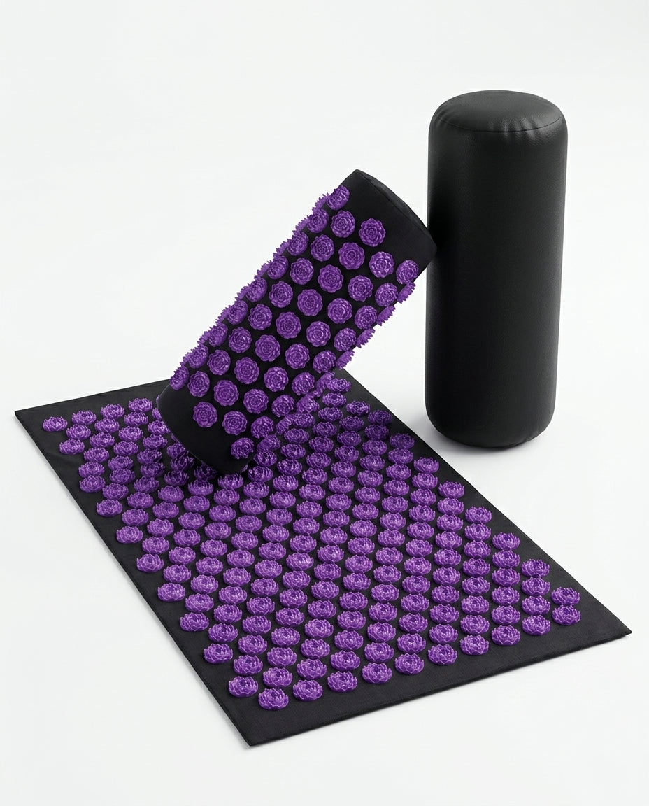 Purple acupressure mat with rolled pillow and bolster, angled view on white