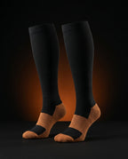Pair of black copper-accent compression socks on a dark glowing backdrop