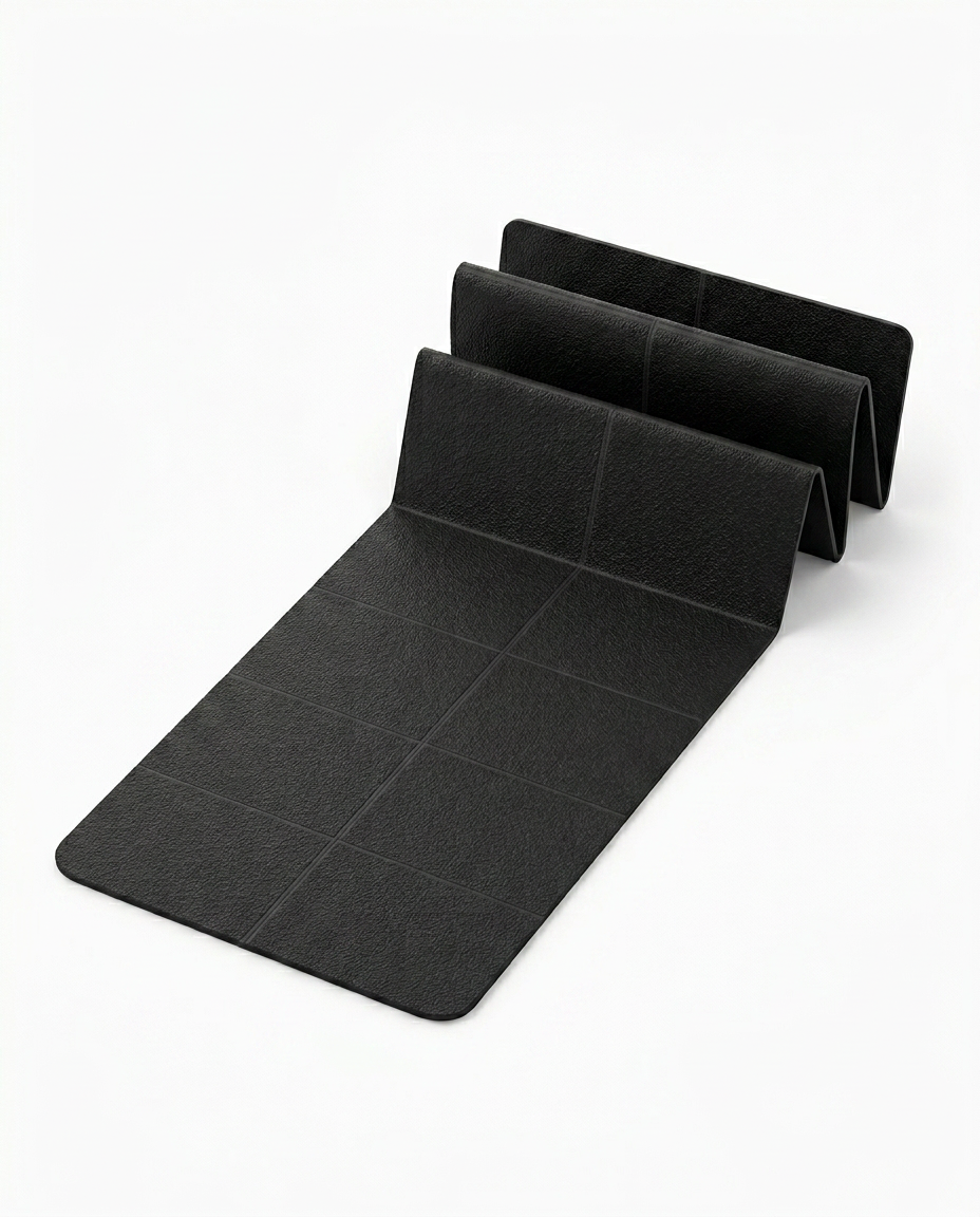 Black foldable yoga mat partly unfolded in accordion panels on white