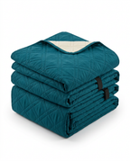 Folded peacock blue quilted recliner chair cover stacked on white