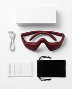 In-box contents flatlay with eye massager, USB cable, manual and pouch