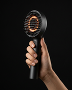 Hand holding the heated scalp massage brush to show its compact size