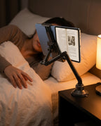 Woman reading an e-book on a tablet held overhead by the bedside mount
