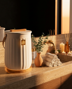 Towel warmer styled on a sunlit guest bathroom counter with rolled towels