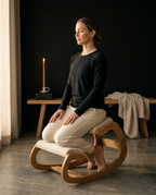 Woman meditating seated on the kneeling chair by candlelight