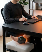 Man at a desk wearing the heated massager wrap on his ankle while working