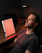 Man relaxing at a desk beside the glowing red light panel