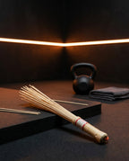 Bamboo massage roller resting in a dark gym beside a kettlebell and towel