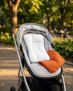 Baby head support pillow placed in a stroller seat at a sunny park