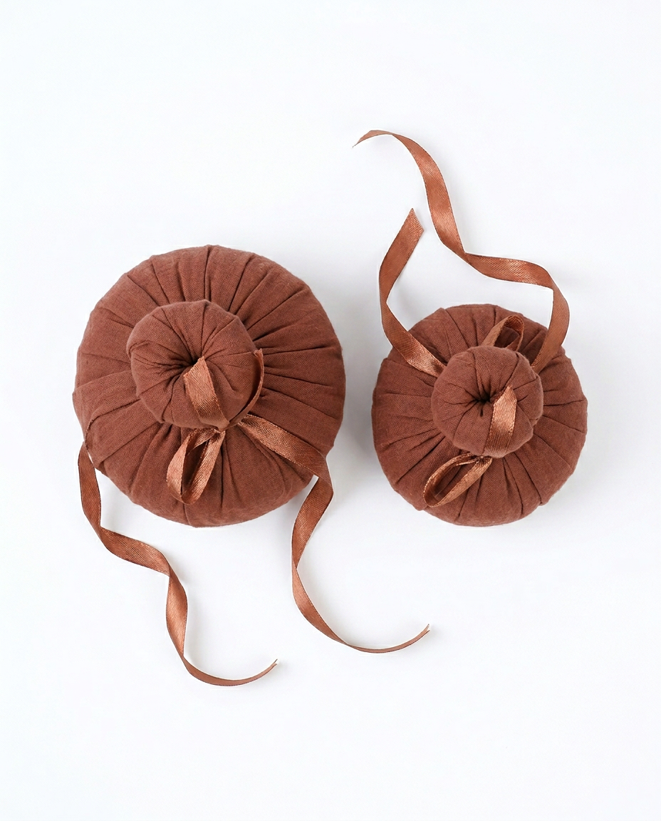 Top-down view of two herbal compress balls with trailing ribbons