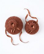 Top-down view of two herbal compress balls with trailing ribbons