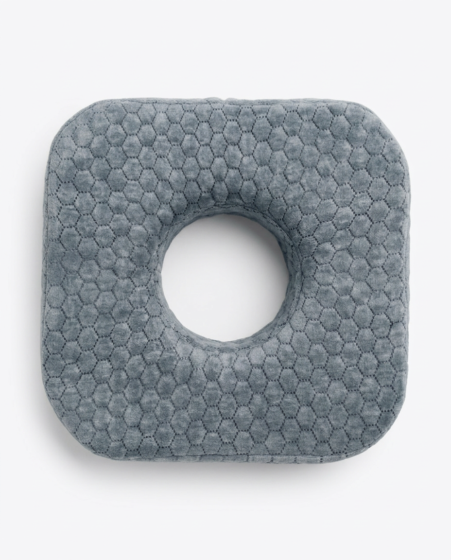 Top-down view of the grey ear piercing pillow with central hole on white