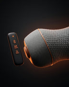 Detail of the black remote with heat, vibration and traction buttons beside the pillow