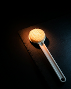 Body brush lit on dark slate, highlighting the dense soft bristle head