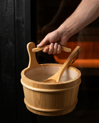 Hand lifting the sauna bucket by its handle to show its size