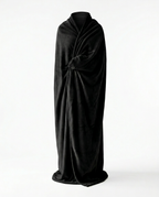 Person wrapped in a black wearable blanket, studio shot
