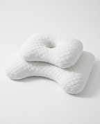 White ergonomic sleep pillow with diamond-quilted cover showing its curved geometry