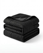 Folded black cooling blanket with satin trim, studio shot on white