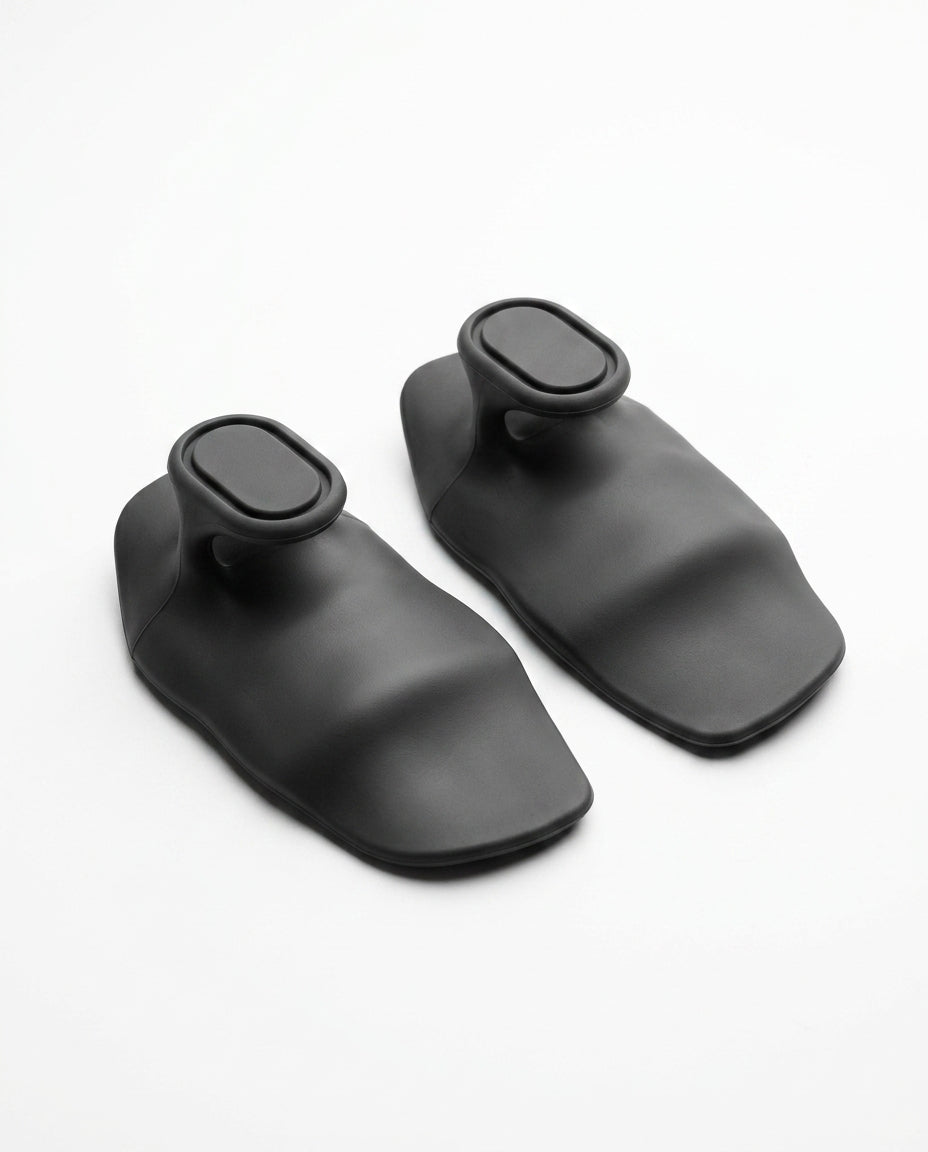 Pair of black silicone grip pads on light grey studio surface